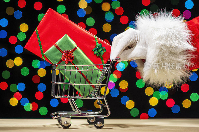 Santa pushing shopping cart full of wrapped big screen TVs against multi-colored bokeh – Concept online shopping
